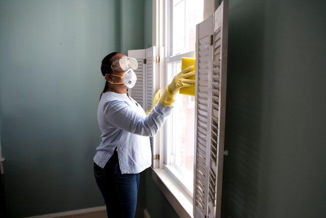 Worker in protective gear cleaning window shutters during a make-ready turn