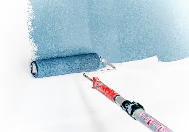 Paint roller applying fresh paint to a wall