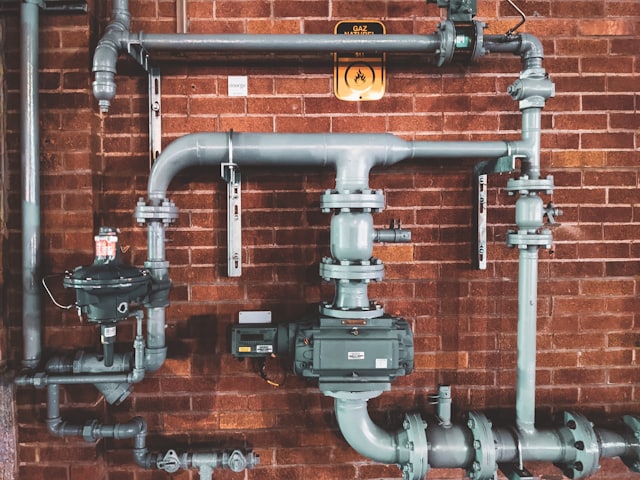 Water and gas pipes with a meter on a brick wall